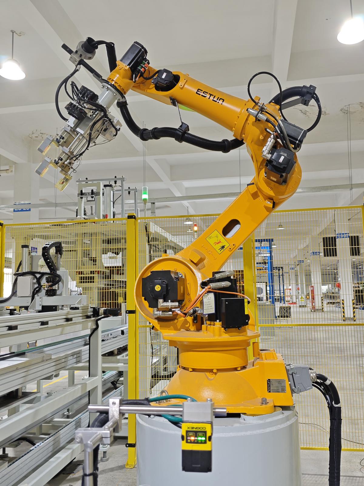 Yellow industrial robot arm behind safety fencing on line 2